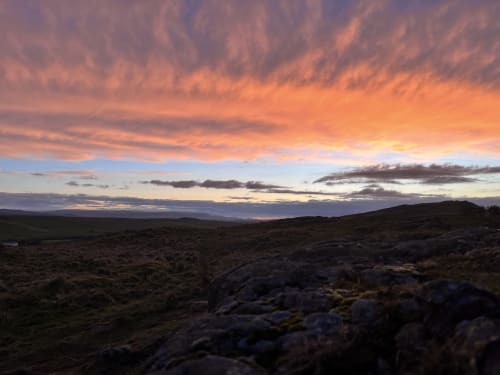 Sunset over moorland near Haydon Bridge, golden sky reflecting across rolling hills and rocky terrain