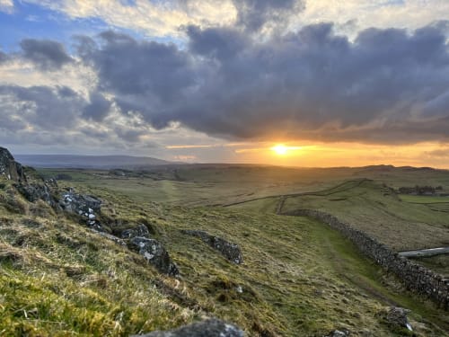 Dramatic sunset over rolling hills and stone walls near The Railway Hotel Haydon Bridge