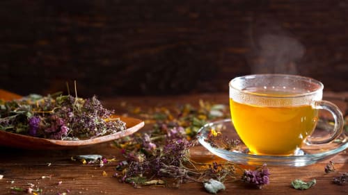 Té herbal humeante con flores púrpuras secas en Hotel Fiori Roma, experiencia de hospitalidad relajante