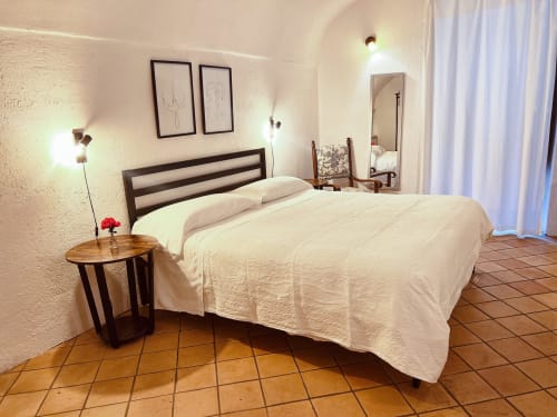 Camera luminosa presso l'Agritusmo Stecadò a Dolceacqua con biancheria bianca, struttura letto in legno, pavimenti in cotto e design moderno