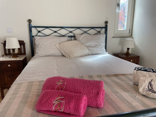 Quarto aconchegante na Star Host Estudio Hortas em Bordeira com cama de ferro, toalhas rosa e vista para as montanhas