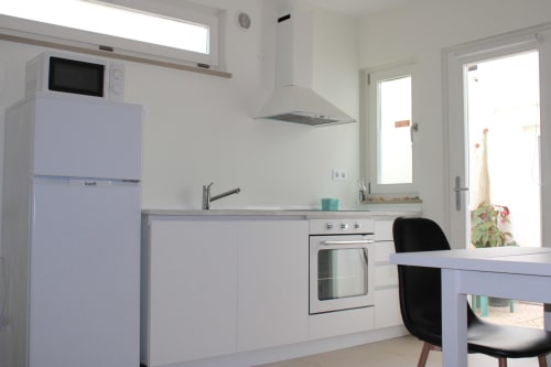 Cozinha moderna no apartamento Estudio Hortas com armários brancos, geladeira azul claro, forno, coifa e área de refeições