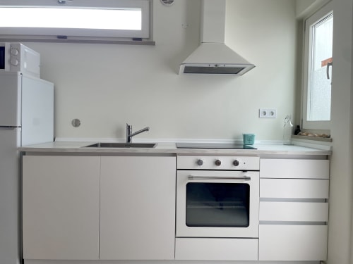 Cozinha moderna branca com forno elétrico, fogão e coifa na Star Host, em Bordeira, Portugal