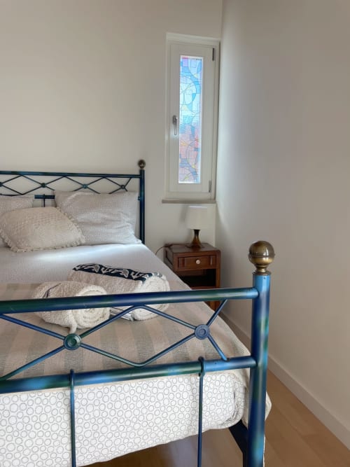 Quarto acolhedor do Star Host Estudio Hortas com cama de estrutura metálica azul e roupa de cama creme em Bordeira, Portugal