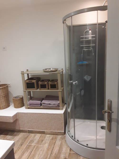 Cuarto de baño moderno de la casa rural Château De Clusors con ducha de cristal curvo, estanterías de madera y decoración rústica
