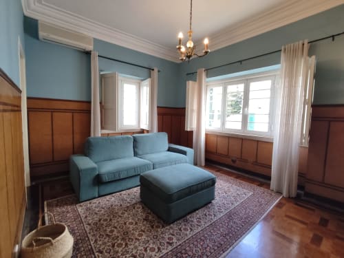 Elegante sala de estar da Villa Sor com sofá azul-petróleo, painéis de madeira e luz natural das janelas em Ponte de Sor