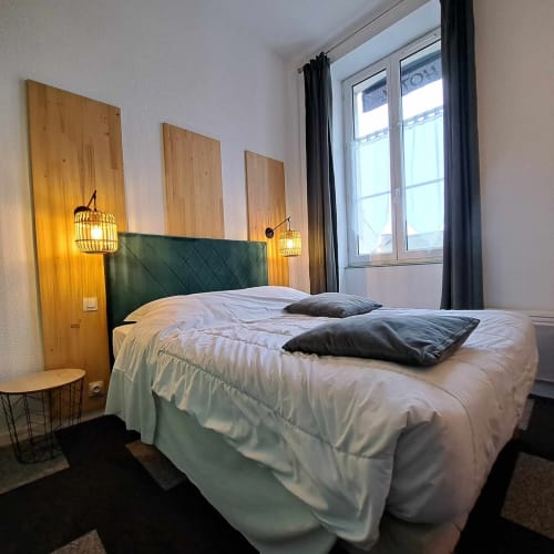 Chambre moderne à l'hôtel Les Deux Porches à Verrières avec lit en tissu vert, décoration murale en bois et luminaires suspendus