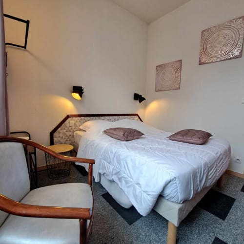 Chambre douillette de l'hôtel Les Deux Porches à Verrières avec lit double, mobilier en bois et décoration murale