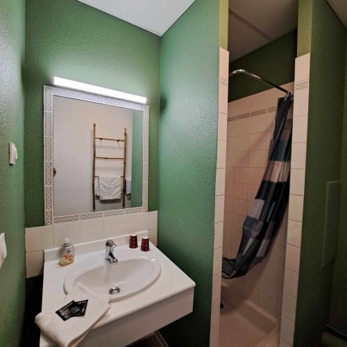 Salle de bains moderne aux Les Deux Porches Verrières avec murs texturés verts, miroir éclairé, lavabo blanc et douche