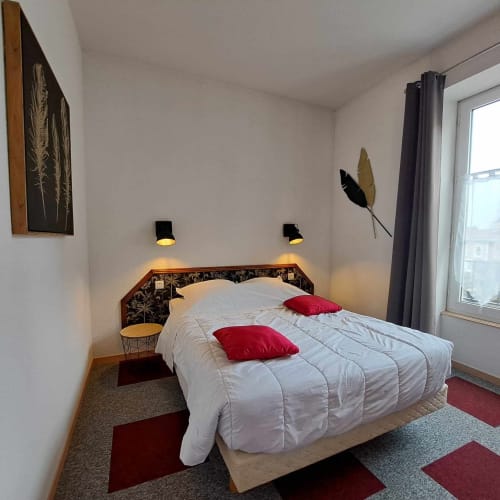 Chambre d'hôtel moderne aux Deux Porches à Verrières avec literie blanche, oreillers rouges et décoration contemporaine