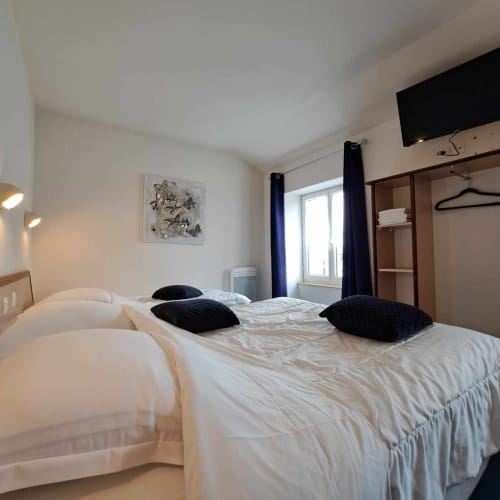 Chambre moderne de l'hôtel Les Deux Porches à Verrières avec lits jumeaux, oreillers noirs et rideaux sombres