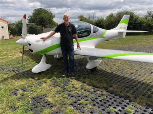 Homme debout à côté d'un avion blanc et vert au terrain d'aviation Les Deux Porches à Verrières, France