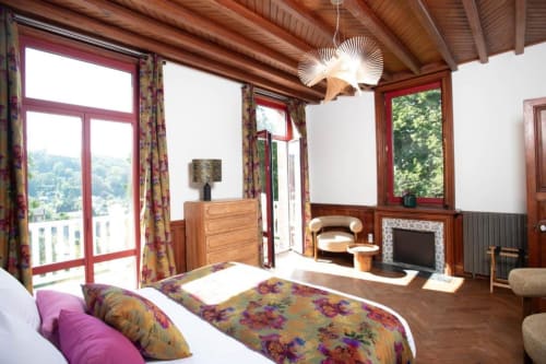 Chambre double de luxe à la Villa Eliane à Étretat avec parure florale, poutres apparentes, cheminée et vue sur le jardin