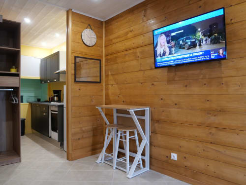 Appartement Sci Saviya à Égletons avec murs en bois, kitchenette, table haute et TV murale