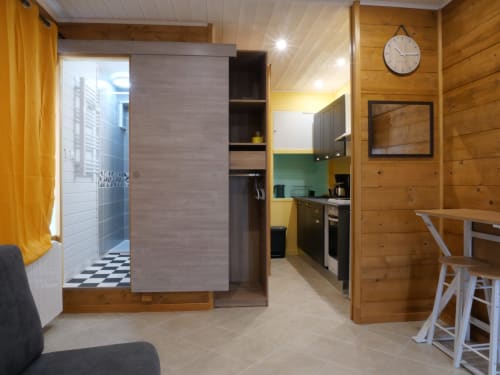 Studio moderne Sci Saviya à Égletons : murs en bois, kitchenette, salle de bain, coin repas et espace nuit