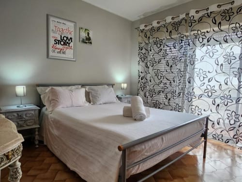 Bright bedroom at Casa do Sol Algarve hotel in Lagos with queen bed, floral curtains, bedside lamps, and decorative wall art