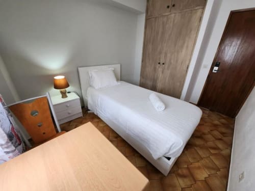 Single bedroom at Casa do Sol Algarve hotel in Lagos with white bed, wooden wardrobes, and terracotta tile flooring