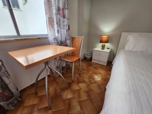 Cozy bedroom at Casa do Sol Algarve in Lagos with wooden desk, chair, bed, and terracotta tiles