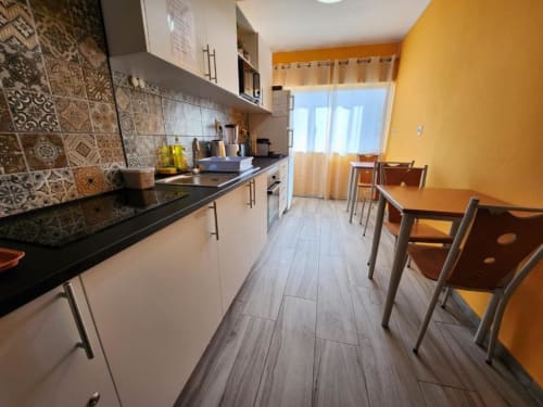 Bright kitchen-dining area at Casa do Sol Algarve in Lagos with white cabinets, decorative tile backsplash, yellow walls, and