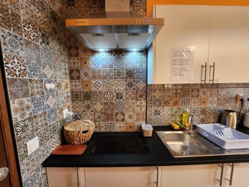Modern kitchen with ornate patterned tiles, black countertop, and stainless steel sink at Casa do Sol Algarve, Lagos