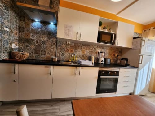 Modern kitchen at Casa do Sol Algarve hotel in Lagos with white cabinetry, patterned tile backsplash, and black countertops.