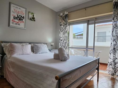 Quarto brilhante na Casa do Sol Algarve em Lagos com roupa de cama branca, móveis modernos e varanda com vista para o branco