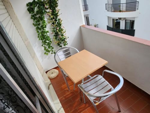 Small balcony seating area at Casa do Sol Algarve Lagos with wooden table, metal chairs and trailing plants