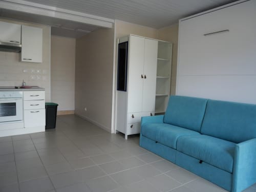 Studio lumineux à Sci Saviya avec canapé turquoise, cuisine blanche et carrelage à Égletons