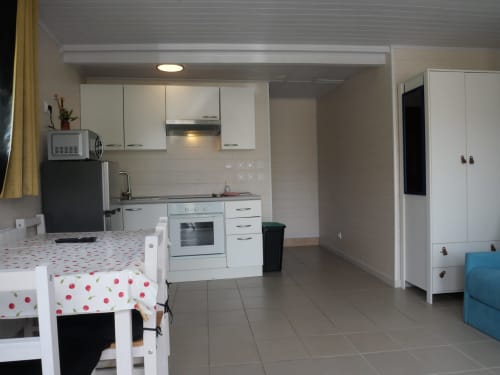 Cuisine-salle à manger moderne au Sci Saviya B&B à Égletons avec mobilier blanc, cuisinière, réfrigérateur et table de repas rouge