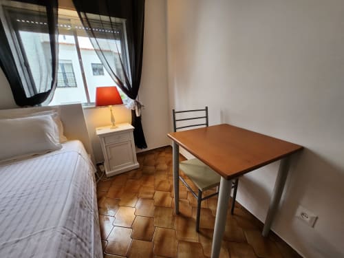 Single room at Casa do Sol Algarve hotel in Lagos with bed, desk, table and terracotta tile floor
