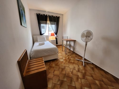 Single room at Casa do Sol Algarve, Lagos with white bed, fan, desk and terracotta flooring