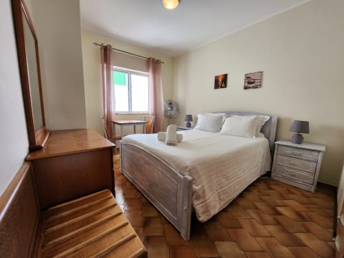 Espaçoso quarto de casal na Casa do Sol Algarve com cama confortável, móveis de madeira e luz natural abundante pela janela