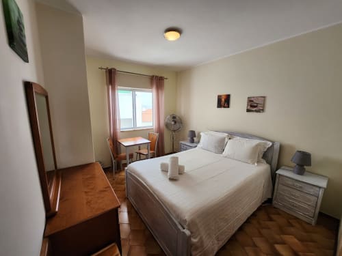 Quarto duplo luminoso em Casa do Sol Algarve Lagos com vista parcial para o oceano, roupa de cama branca, móveis em madeira e área de trabalho
