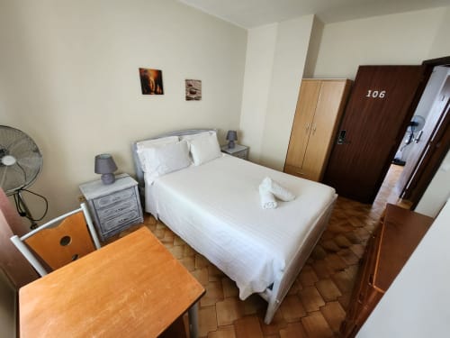 Quarto duplo com cama branca, móveis de madeira e ventilador no hotel Casa do Sol Algarve em Lagos, Portugal
