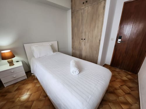 Single bedroom at Casa do Sol Algarve Lagos with white bed, wooden wardrobe, nightstand and terracotta floor