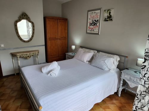 Quarto de casal luminoso em Casa do Sol Algarve em Lagos com roupa de cama branca, guarda-roupa de madeira, espelho ornamentado e vista para a cidade