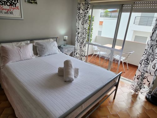 Quarto de casal brilhante com varanda na Casa do Sol Algarve, Lagos. Cama branca, cortinas florais, terraço com vista para a cidade, moderno