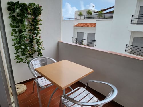 Varanda mobiliada na Casa do Sol Algarve em Lagos com mesa, cadeiras, plantas floridas e vista para a cidade