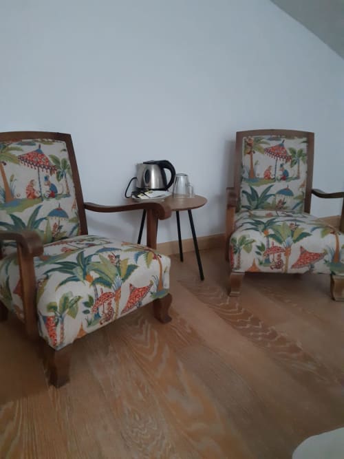 Chambre double confortable à Casa Rural La Perla avec fauteuils fleuris, table d'appoint en bois et bouilloire dans un gîte rural espagnol