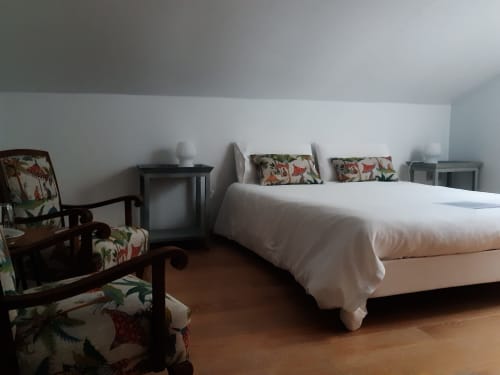 Spacieuse chambre double à Casa Rural La Perla avec lit blanc, fauteuils floraux et parquet en bois à Hiendelaencina