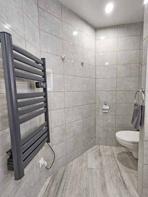 Modern bathroom at Domaine à l'Aise with heated towel rack, walk-in shower, and light wood-grain flooring
