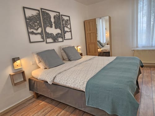 Modern bedroom at Domaine à l'Aise with queen bed, gray bedding, wooden nightstand, wall art, and mirror