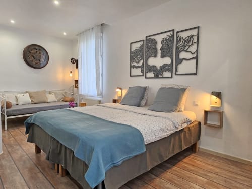 Modern bedroom at Domaine à l'Aise with queen bed, daybed, gray bedding, wall art, and garden view in Saint-Pargoire