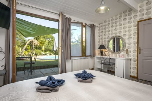 Bright bedroom at Domaine à l'Aise with pool view, modern amenities, patio doors, and welcoming decor in Saint-Pargoire