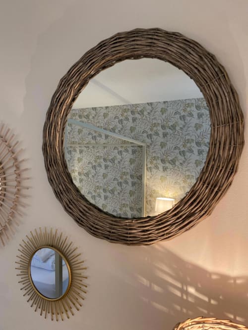 Woven rattan mirror reflecting botanical wallpaper in Verdolivo B&B, Sale Marasino