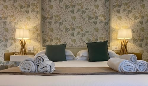 Luxuriöses Bett im Verdolivo B&B mit aufgerollten Handtüchern, grünen Kissen und botanischer Tapete in Sale Marasino