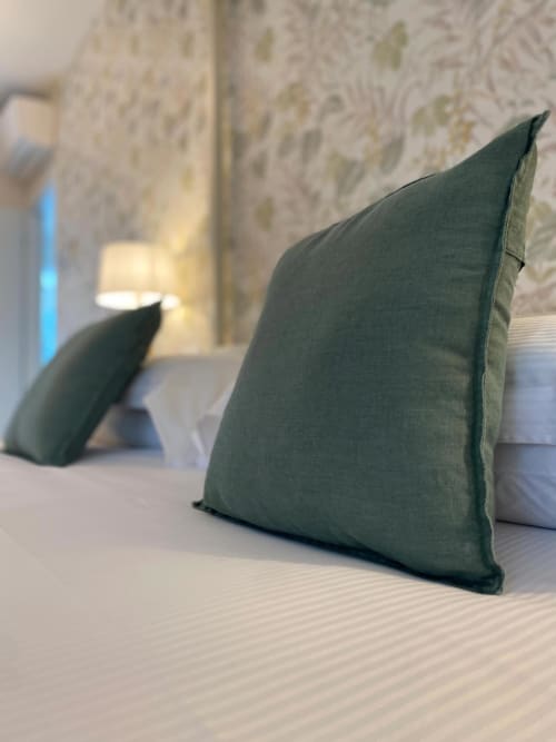 Green linen pillows on bed at Verdolivo B&B in Sale Marasino, with textured wall backdrop