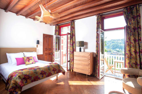 Bright double deluxe bedroom at Villa Eliane in Étretat with wooden beams, floral bedding, and balcony overlooking the garden
