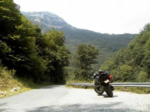 Motorcycle on winding mountain road near Les Arcs, French Alps forest landscape