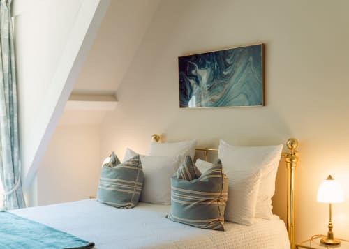 Elegant bedroom at Domaine de Bize with white bedding, striped cushions, abstract wall art, and brass lamp in Mirepoix,